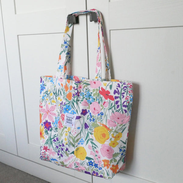 Floral-patterned tote bag hanging on a white door
